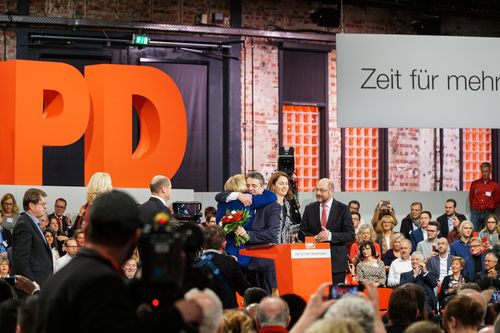 Ritualisierte Geschenkübergaben und gemeinsame Auftritte von Parteifunktionären zählen auf Parteitagen zu den wichtigsten visuellen, inszenatorischen Mitteln. Sie demonstrieren nicht nur innerparteiliche Geschlossenheit, sondern sind auch beliebtes Fotomotiv für hunderte Medienvertreter. Gleich doppelt wurde der scheidende Parteivorsitzende Sigmar Gabriel daher beschenkt – erst überreicht Nachfolger Martin Schulz ein Porträt von August Bebel, dann zieht der Parteivorstand mit einem Blumenstrauß aus roten und weißen Rosen nach.