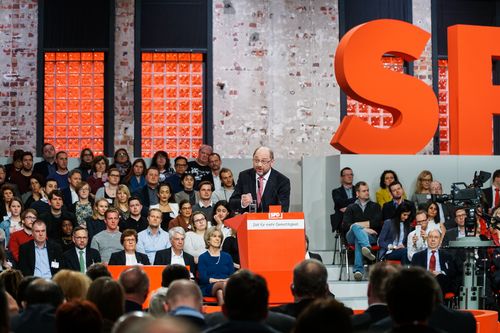 Dass der gerade gewählte Parteivorsitzende Martin Schulz nicht vor einer schlichten Leinwand, sondern vor „lebendigem“ Hintergrund spricht, ist das inszenatorische Novum des Parteitages. Die Tribüne mit Ehrengästen und Neumitgliedern ist damit der omnipräsente Hintergrund aller Bilder und soll einen bunten Querschnitt durch die Anhänger der SPD zeigen. Auch durchmischt sie gekonnt Funktionäre und einfache Gäste: So sitzt dort etwa Michael Roth, Staatsminister für Europa im Auswärtigen Amt, dicht gedrängt an neue Parteimitglieder aus ganz Deutschland. Doch auch Risiken birgt dieser Aufbau: Wer bei all der Aufregung ein kurzes Nickerchen einlegt, bekäme wohl genauso viel Aufmerksamkeit wie der frisch gebackene Kanzlerkandidat.  