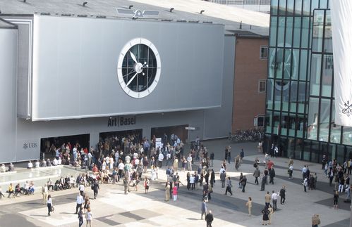 Zum 48. Mal findet die Art Basel – hier das Eingangstor zur Halle im Jahr 2011 – aktuell statt. In der weitläufigen Messehalle 1 erwarten die Besucher 76 großangelegte Werke. Und genau mit diesen Kunstwerken gelingt der Art Basel in diesem Jahr, was die documenta in Kassel oder die Biennale in Venedig hätten schaffen sollen, lobt etwa die Frankfurter Allgemeine Zeitung: „Unübersehbar ist die Abkehr von der vorübergehend zur Norm erhobenen Entsinnlichung. Die allfälligen ,Post‘-Ismen, die da postmodern oder zuletzt postdigital hießen, sind abgedankt. Es lässt sich nur vermuten, dass eine neue junge Generation keine Lust mehr hat auf Entkörperlichung und zerfließende Identität.“ Insgesamt 291 Aussteller aus 35 Länder sind dieses Mal in Basel dabei – der Schwerpunkt liegt überwiegend auf Europa und westlicher Kunst. Damit leistet die Kunstschau einen wichtigen Beitrag dazu, das abzubilden, was der Markt gerade hergibt. „Und in dieser Abbildungsfunktion übertrifft sie schlicht jede andere Leistungsschau dieser Art. Die Art Basel ist und bleibt der Seismograph für diese Bewegungen.“