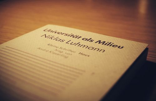 Niklas Luhmann wurde am 8. Dezember 1927 als Sohn eines Brauereibesitzers in Lüneburg geboren und starb am 6. November 1998 in Oerlinghausen bei Bielefeld. Im Alter von 17 Jahren wurde er als Luftwaffenhelfer eingezogen und war 1945 in amerikanischer Kriegsgefangenschaft. Von 1946 bis 1949 studierte er Rechtswissenschaften in Freiburg und absolvierte seine Referendarausbildung. 1952 begann er mit dem Aufbau seiner berühmten Zettelkästen. Luhmann erhielt 1960 und 1961 ein Fortbildungsstipendium für die Harvard University. Dort kam er in Kontakt mit Talcott Parsons und dessen strukturfunktionaler Systemtheorie. 1964 veröffentlichte er sein erstes Buch „Funktionen und Folgen formaler Organisation“. 1966 wurden „Funktionen und Folgen formaler Organisation“ sowie „Recht und Automation in der öffentlichen Verwaltung“ als Dissertation und Habilitation an der Universität Münster angenommen. Von 1968 bis 1993 lehrte Luhmann als Professor für Soziologie an der Universität Bielefeld. 1997 erschien sein Hauptwerk, das Resultat dreißigjähriger Forschung: „Die Gesellschaft der Gesellschaft“.