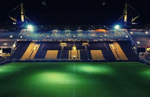 Hätte man den Dortmundern vor 30 Jahren von einem Fußballtempel mit über 80.000 Plätzen inmitten ihrer Stadt erzählt, von einem Stadion mit Glasfassade, Rasenheizung und der größten Stehplatztribüne Europas, alle hätten ob derlei Fantastereien nachsichtig gelächelt. Heute steht an der Strobelallee mit dem Signal Iduna Park tatsächlich Deutschlands größtes Fußballstadion. Fassungsvermögen: Exakt 81.365 Plätze. Herzstück: Die Südtribüne. Sie kann Spiele entscheiden. Sagt man. Sie ist ein Organismus, ein eigener Mikrokosmos. Ein Ort für den Fußball und die Fans. Wenn nicht gerade eine Pandemie auch die Fußballwelt in Atem hält, verwandelt sich ihr betongrau alle zwei Wochen in leuchtendes schwarzgelb. Dann hauchen knapp 25.000 Menschen der Süd ihr Leben ein. Wer einmal auf ihr gestanden hat, kann sich ihrer Faszination kaum mehr entziehen. Auf 6.900 Quadratmetern liegen (oder besser: stehen) Freude, Ekstase, Wut, Enttäuschung und grenzenloser Jubel so nahe beieinander wie sonst nirgendwo.